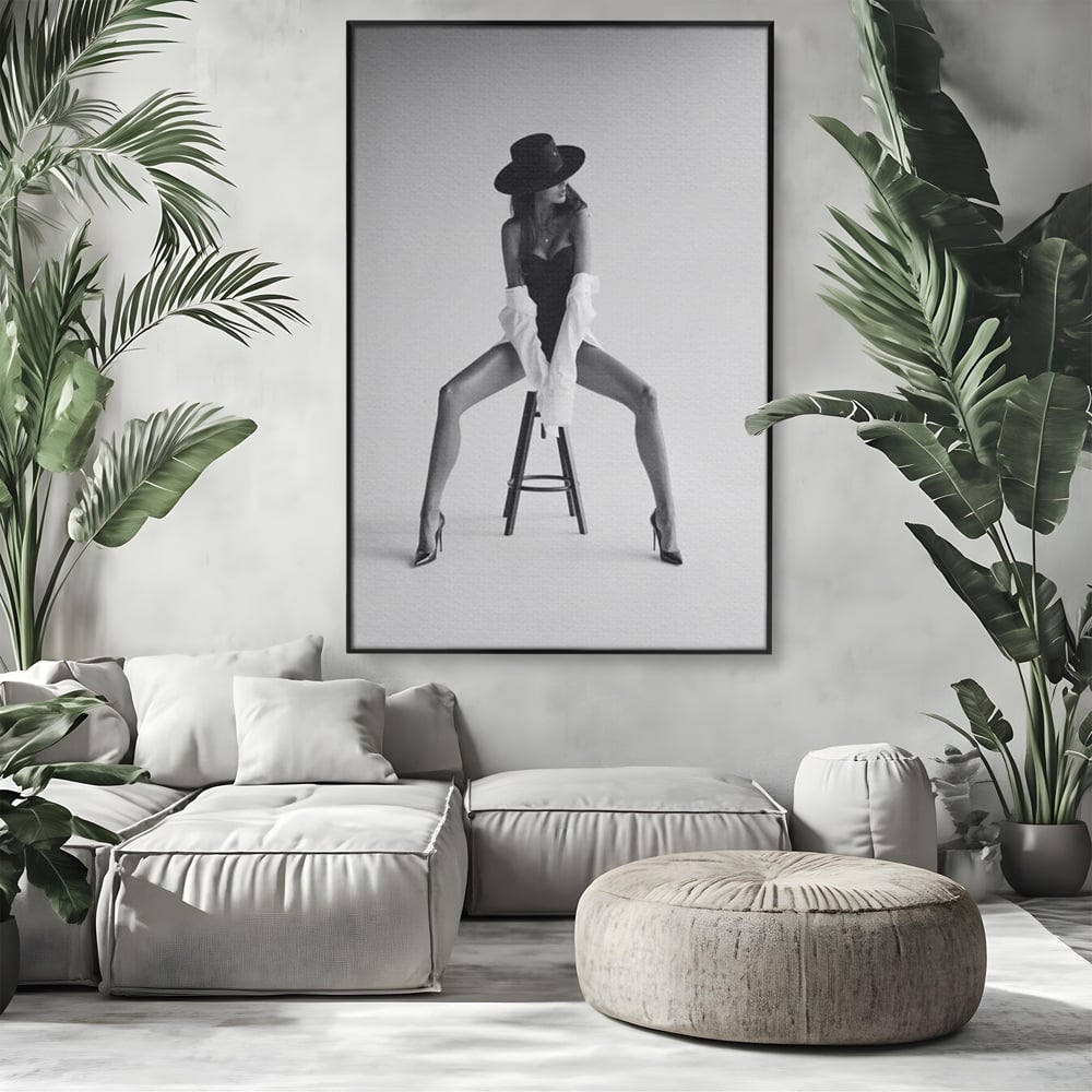Tablou canvas cu tablou canvas cu femeie pe scaun, in rama de aluminiu negru, pe perete intr-un living